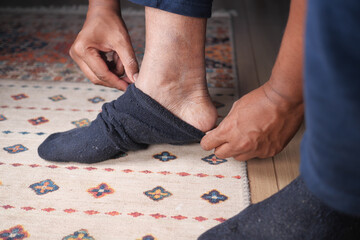 Person putting on sock in cozy indoor setting