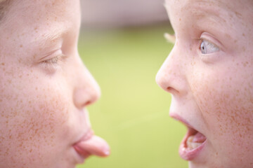 Tongue out, happy kids or sisters in nature playing for bond on holiday together with surprise or joy. Park, games or faces of children siblings in field with shock, teasing or friendship in a garden
