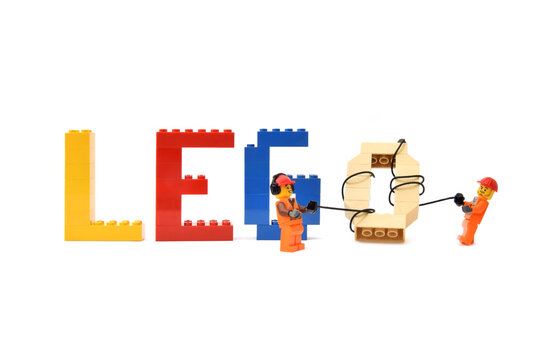 Lego minifigures of workers in uniform are making a word lego from letters are made from bricks. Editorial illustrative image of popular plastic toy constructor.