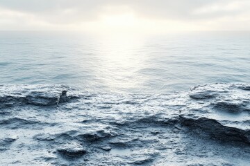 Sea view from atop rocky cliffs. The water sparkles under a cloudy sky, near the horizon