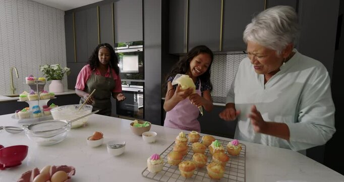 Decorating cupcakes together, three generations in kitchen, enjoying diverse family time