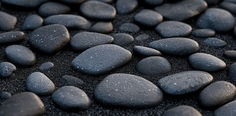 A close-up view of smooth. rounded pebbles scattered on a dark sandy surface. showcasing their natural textures and colors. ideal for backgrounds or nature-themed projects