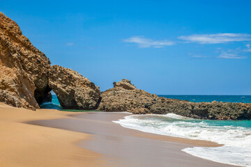 Waves crashing on urama beach against a rocky arch in la guaira, venezuela