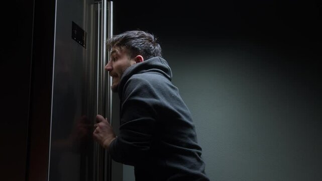 Man caught sneaking snacks from kitchen at night looking startled in dark hallway