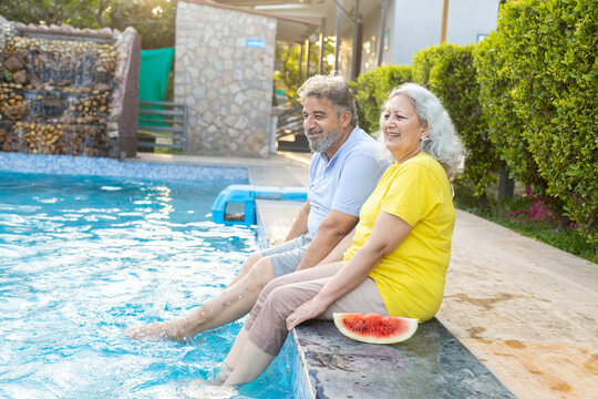 Summer holiday- Retired senior indian couple relaxing at swimming pool, Elderly husband wife enjoy at hotel resort vacation. Retirement life.