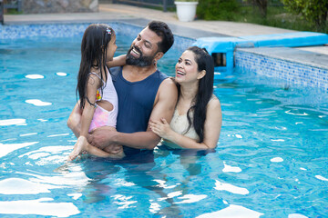 Young indian family enjoy in swimming pool in summer holiday-,India parents with child daughter...