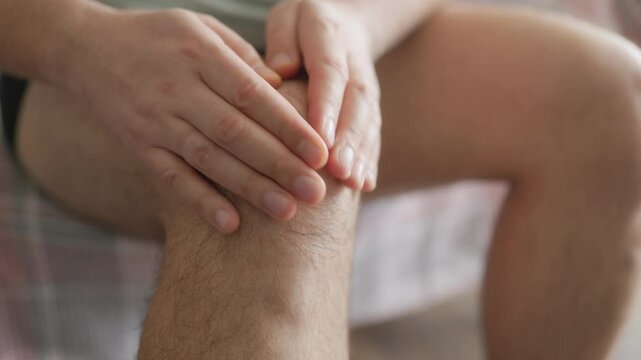 Man applying cream to painful knee joint, close-up home treatment