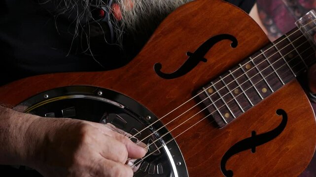 Male musician hand play Vintage Resonator acoustic dobro blues slide guitar.
