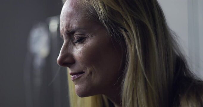 Close-up of woman with pained expression and closed eyes, emotional moment during treatment or diagnosis in medical setting