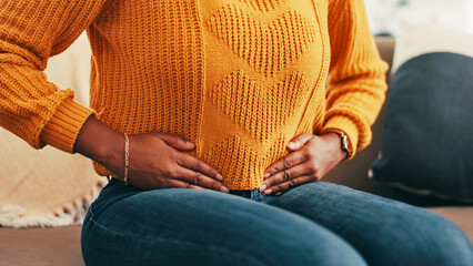 Hands, woman and stomach cramps at house for period pain, digestion problem and menstruation cycle. Person, upset abdomen and discomfort of constipation, appendicitis emergency and colon inflammation