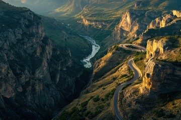 A winding road traverses a scenic mountainous canyon landscape with river