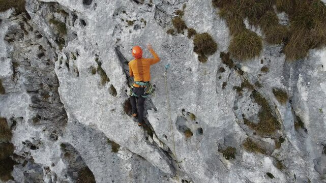 Climber ascending rock wall in scenic outdoor mountain landscape - Arrampicatore che scala parete rocciosa in paesaggio montano