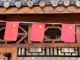 Chinese flags hanging on a traditional wooden building.