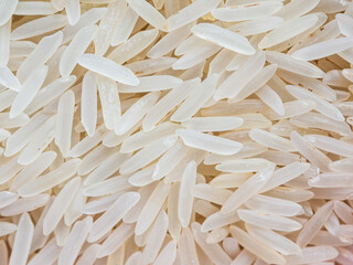 Close-up shot of dry, uncooked long grain basmati rice. Grains are slender and translucent, natural texture.