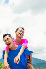 Two Happy Men Piggyback Riding Outdoors Under a Sunny Sky