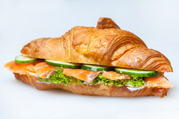 Croissant sandwiche with salmon and green parsley. Croissants with red fish on wooden cutting board. Healthy breakfast. Appetizer. Starter meal