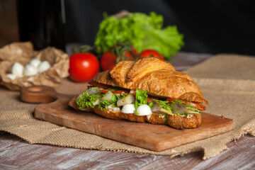 Croissant sandwiche with salmon and green parsley. Croissants with red fish on wooden cutting board. Healthy breakfast. Appetizer. Starter meal