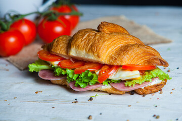 Croissant sandwiche with salmon and green parsley. Croissants with red fish on wooden cutting board. Healthy breakfast. Appetizer. Starter meal