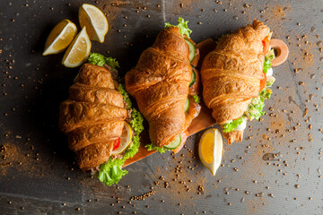 Croissant sandwiche with salmon and green parsley. Croissants with red fish on wooden cutting...