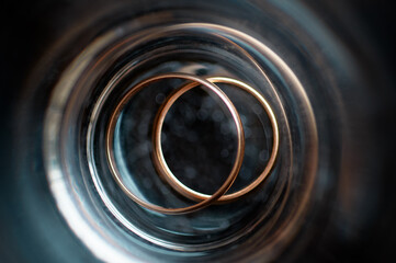 Close-Up View of Gold Wedding Rings in Artistic Cylindrical Frame..