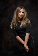 Young Woman in Black Outfit Posing Against a Dark Artistic Background..