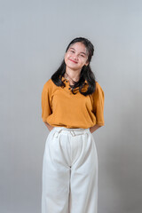 Fototapeta premium Happy young Asian woman smiling with a cheerful facial expression, slightly tilting her head and looking content. Studio portrait showing positivity, friendliness, and warmth.