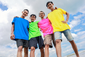 Obraz premium Four Young Men Posing Together Outdoors in Colorful Shirts