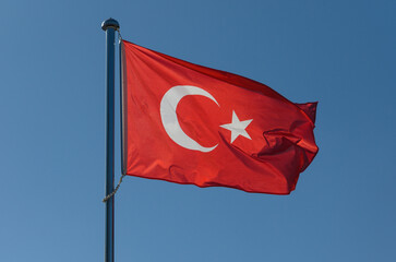 Majestic Turkish flag waves in bright blue sky, symbolizing national pride and heritage during a sunny day