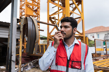 Man, Engineer, Construction site, Job site. Engineer construction worker controlling crane operation at construction site. Control of work and construction area