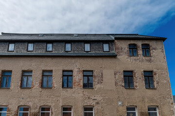 Fototapeta premium Old stone building with multiple windows under a cloudy sky in a quaint town setting
