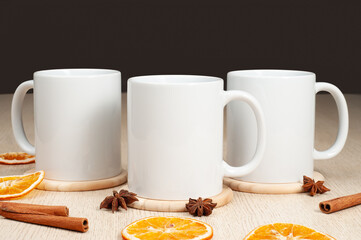 Three Blank 11oz white mugs on on the table. Mugs with warm spices like cinnamon, star anise, dried orange. Mug mockup
