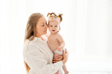 a mother with a baby daughter, a mother gently hugs her baby girl kissing, maternal love and care, a happy family with a baby on a white isolated background, a place for text