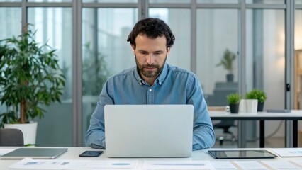 Digital Identity + Biometric Authentication + Security concept, Focused man working on a laptop in a modern office environment.