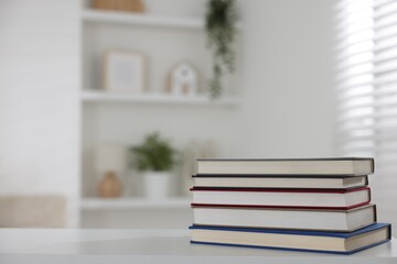 Stack of books on white desk indoors. Space for text