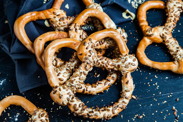 Fresh prepared homemade soft pretzels. Different types of baked pretzels with seeds on a black background