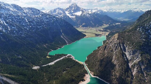 Aerial drone view of the beautiful Heiterwanger See Lake, located in the Austrian Alps. A view of crystal-clear waters, a sunny day and majestic mountains all around. 
