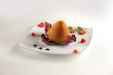 rice ball with meat sauce, Italian arancino, served with tomato, radicchio and basil on a white plate. dish on a white background.