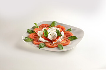 Italian caprese salad with sliced tomatoes, mozzarella, olive oil, oregano and basil leaves
