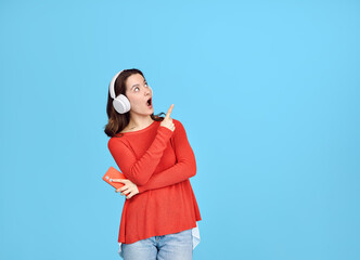 A surprised girl in headphones points her finger at the empty space above.