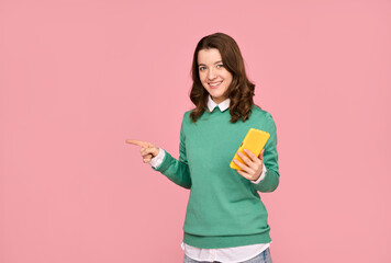 Young woman with smartphone pointing left, isolated on pink background.