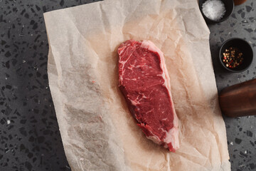 Raw new york sirloin steak on parchment paper warming up before cooking top view