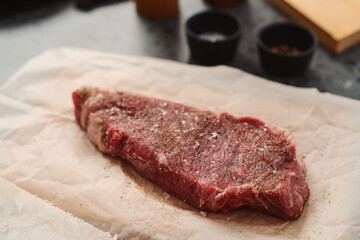 closeup raw seasoned new york steak on concrete countertop background
