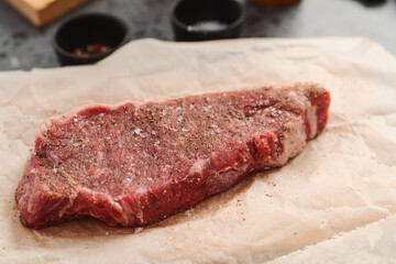 closeup raw seasoned new york steak on concrete countertop background