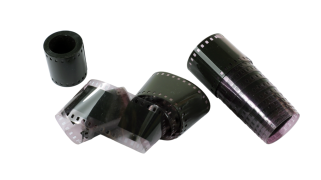 Multiple rolls of old black and white photographic film are arranged on a flat surface, showcasing their diverse textures and shapes. Nostalgic relics from the past tell stories of captured moments.