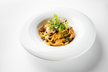 A plate of fettuccine pasta is elegantly topped with sautéed vegetables and fresh greens. The dish showcases a delicious combination, perfect for Italian cuisine enthusiasts.
