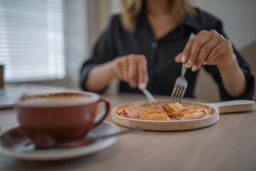 An Asian female student is sitting at a table in her office eating pizza.