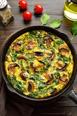 Frittata with spinach and champignon mushrooms in cast iron skillet