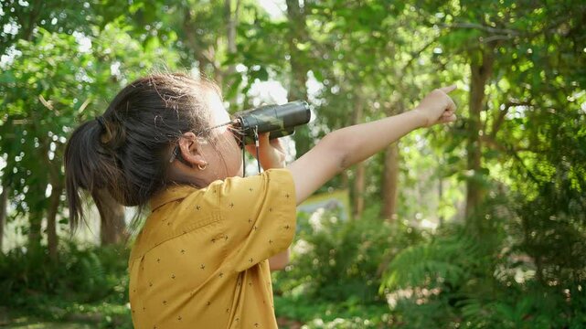 ild exploring nature with binoculars in a lush green forest
