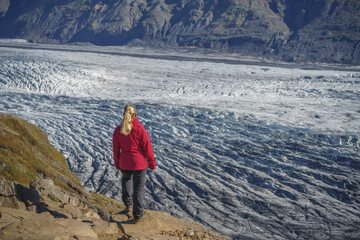 Obraz premium Female solo Hiker Observing Melting Skaftafellsjökull glacier in Iceland's Vatnajökull National Park.she is a environmentalist and worried about greenhouse effect affecting climate change.