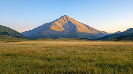 Majestic mountain peak surrounded by lush green fields under clear blue sky